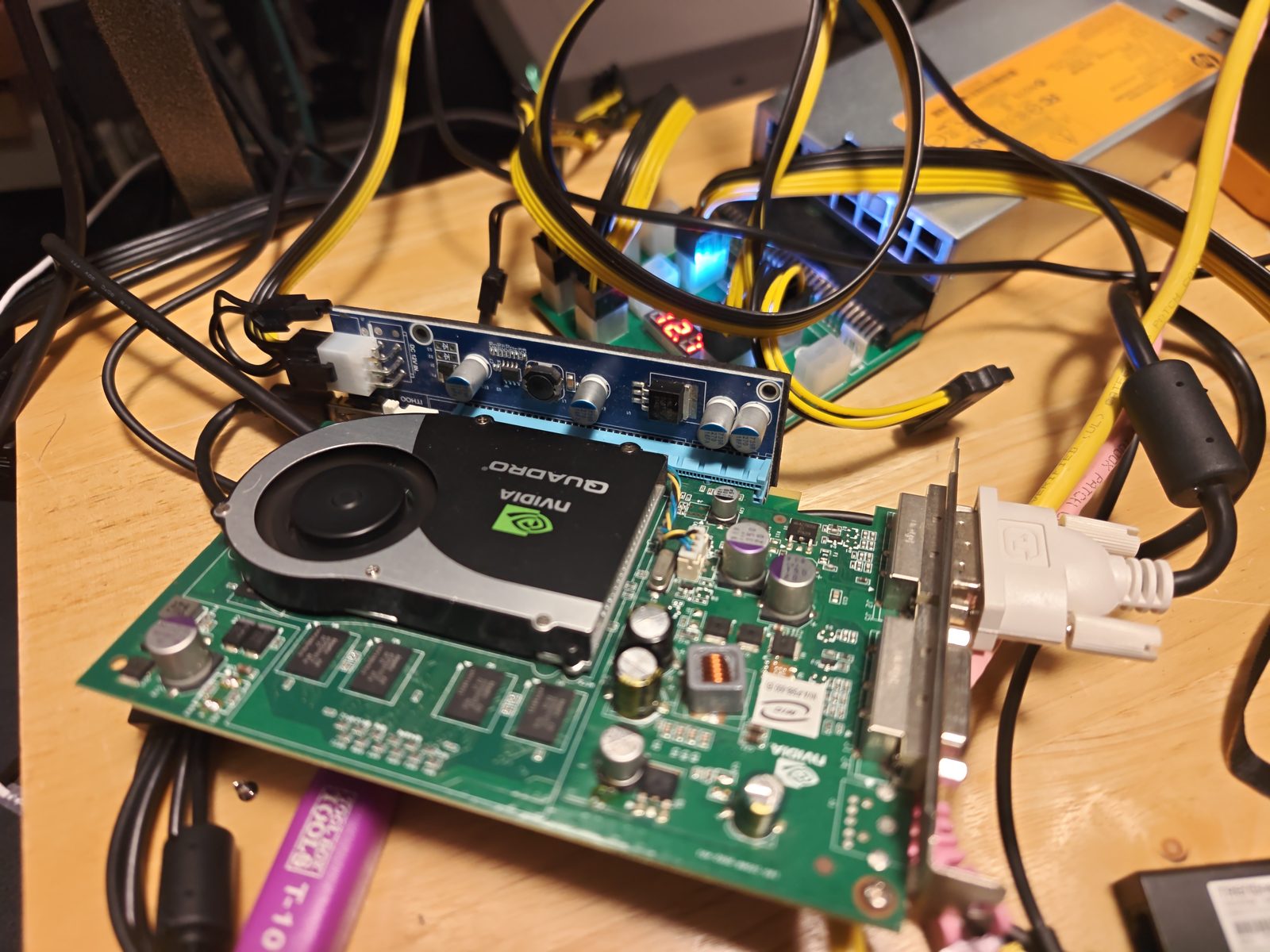 An NVIDIA Quadro card seated in a blue PCIe riser board, powered by a server power supply on a breakout board with yellow cables