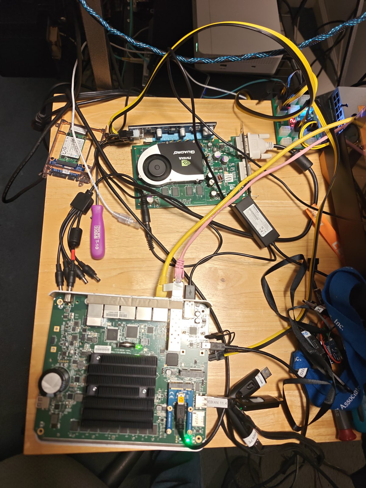 The Edge 540 board out of its case on a wooden bench, connected through a mini-PCIe riser to an NVIDIA Quadro graphics card, with USB sticks and cables all around