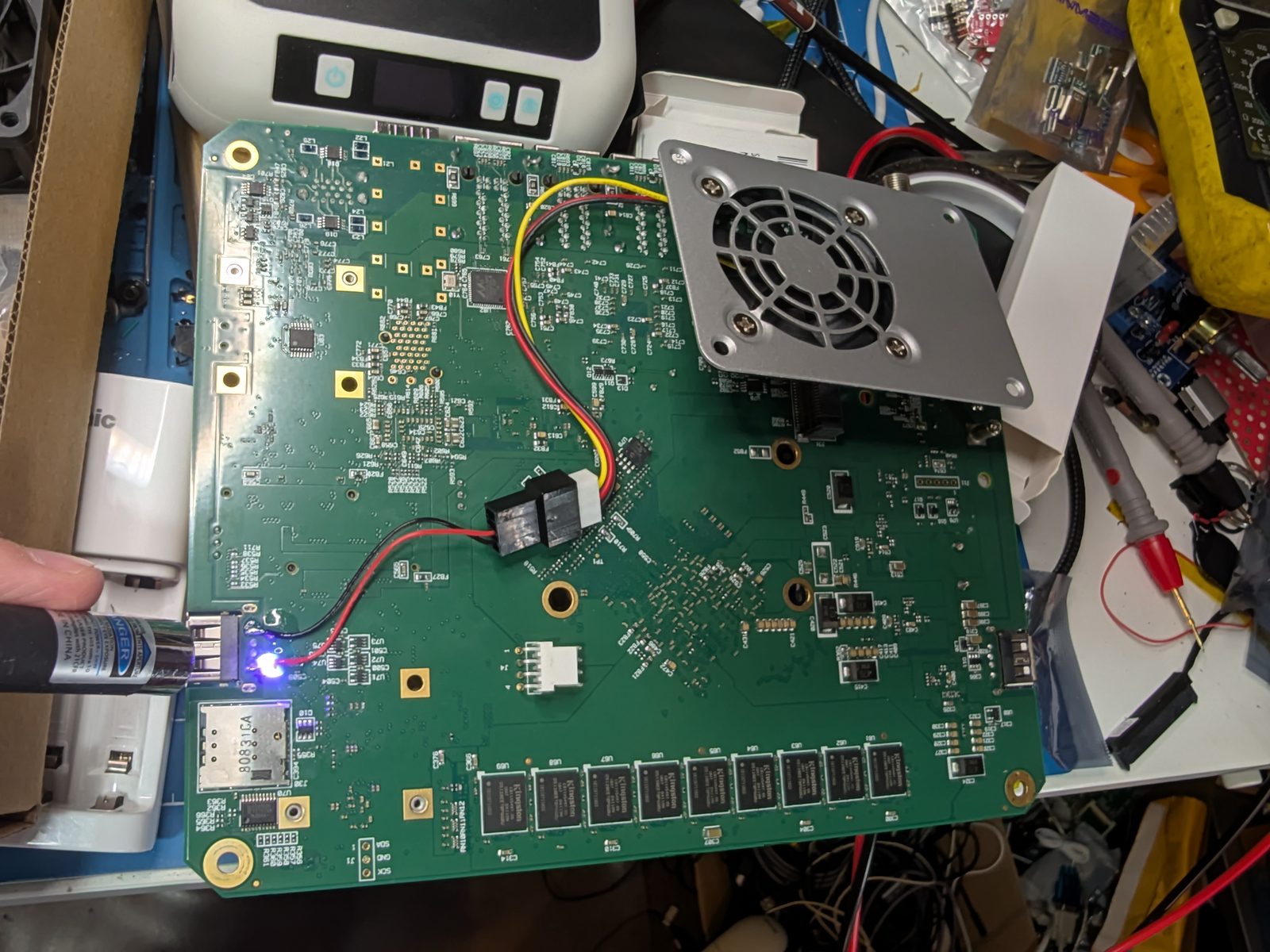 The underside of the Edge 540 board with a soldering iron attaching red and black wires from the USB power rail to a fan connector