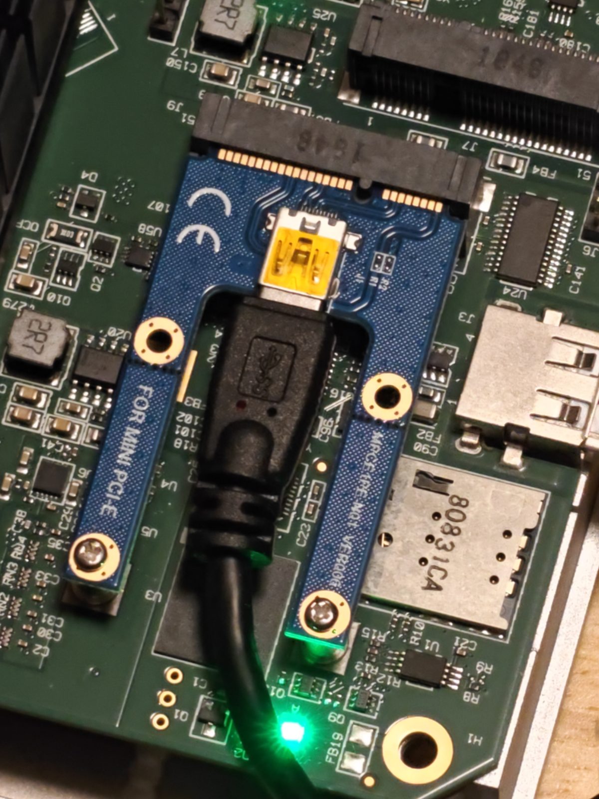 A small blue mini-PCIe adapter board seated in one of the Edge 540's mini-PCIe slots, with a USB cable plugged into it